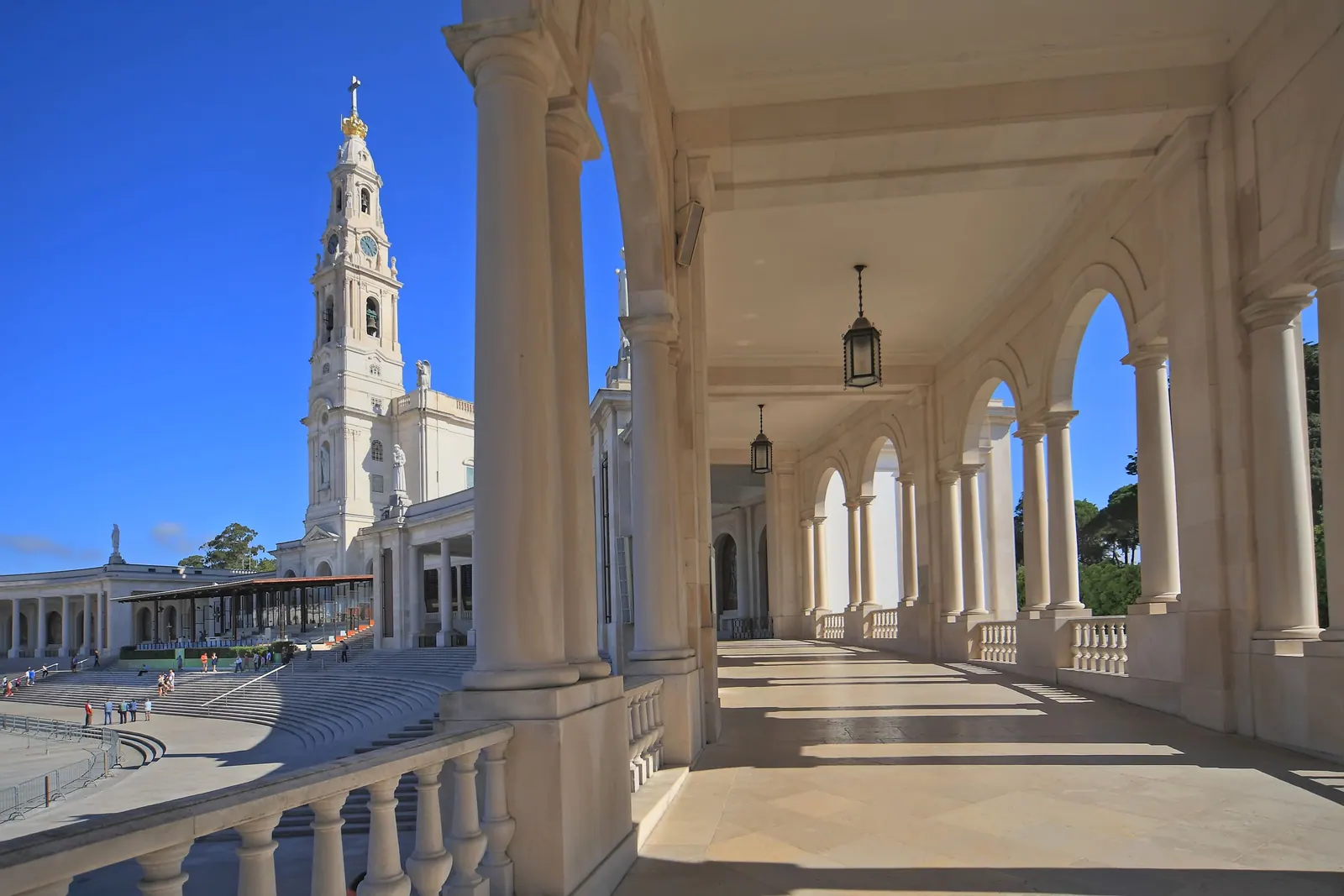 Basílica de Nuestra Señora del Rosario de Fátima vista desde la columnata blanca del santuario, bajo cielo azul